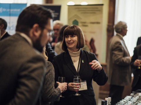 a woman talking to someone while holding a drink 